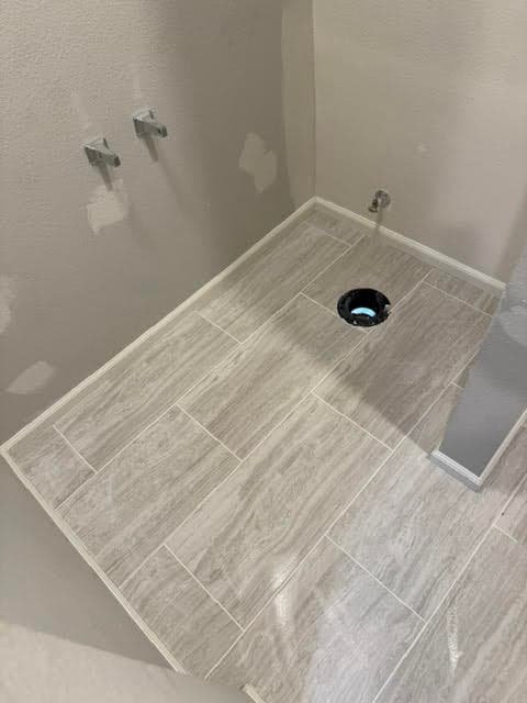 Freshly laid gray plank-style tile floor in a bathroom with the toilet flange exposed