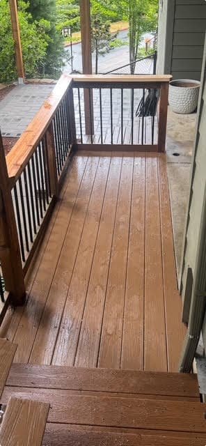 Freshly stained brown deck boards and railing with black metal balusters