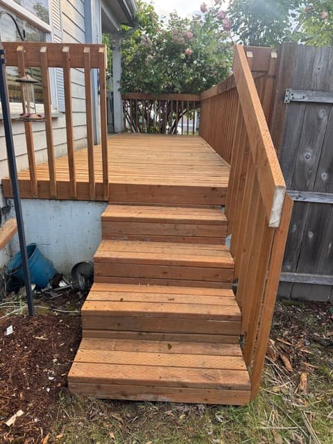 New wooden staircase and railing leading up to a backyard deck