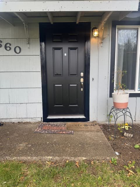 New black front entry door with fresh trim on a light gray house