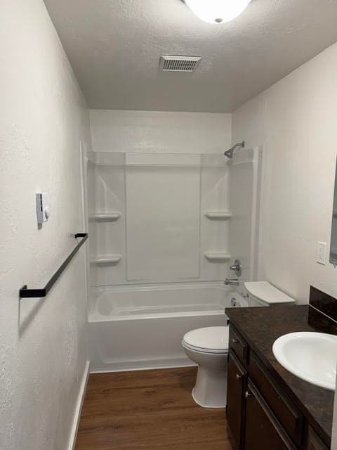 Remodeled bathroom with white tub and shower surround, dark wood vanity, and black towel bar