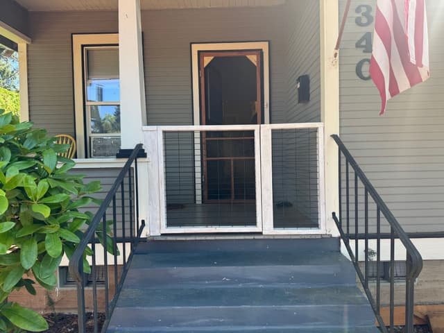 White custom wood-framed wire gate enclosing a front porch