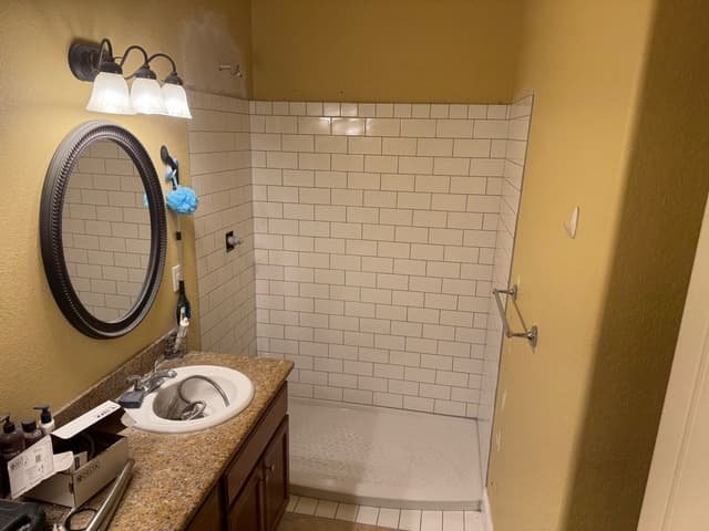 Walk-in shower mid-remodel with new white subway tile surround and shower pan