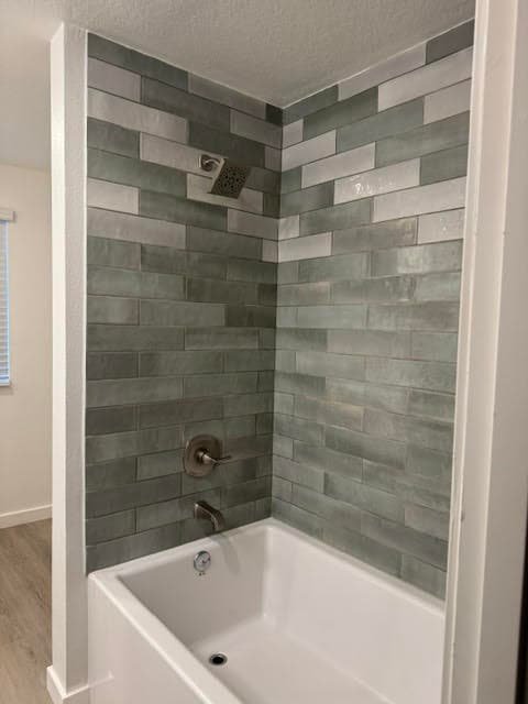 Tub and shower surround finished in green-gray subway tile with brushed fixtures