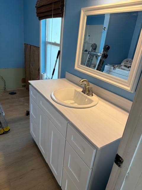 White vanity with new countertop, sink, and brushed nickel faucet in a blue bathroom under renovation